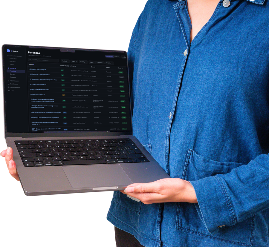 Pessoa segurando um portátil aberto com o IA Engine na tela de Functions: uma tabela de APIs publicadas, cada linha com método HTTP, endpoint, domínio, equipa e estado ativo.